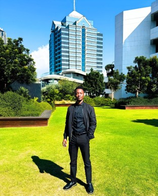 Lebogang standing in the gardens outside Investec. Showing the tall buildings in Sandton.